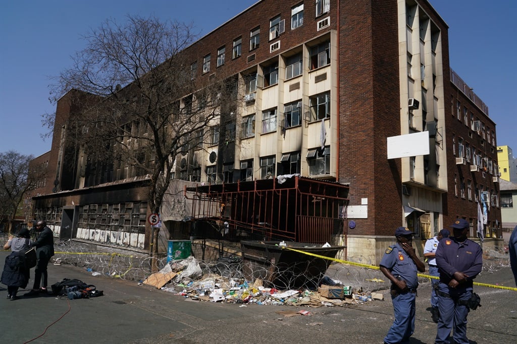 President Cyril Ramaphosa (C) speaks to journalists at the scene where more than 70 people were killed in a building fire in Johannesburg on 31 August 2023. 